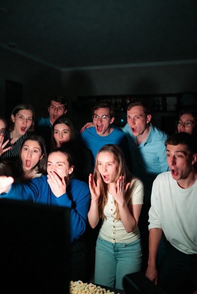 Shocked friends watching TV in dark room, popcorn scattered